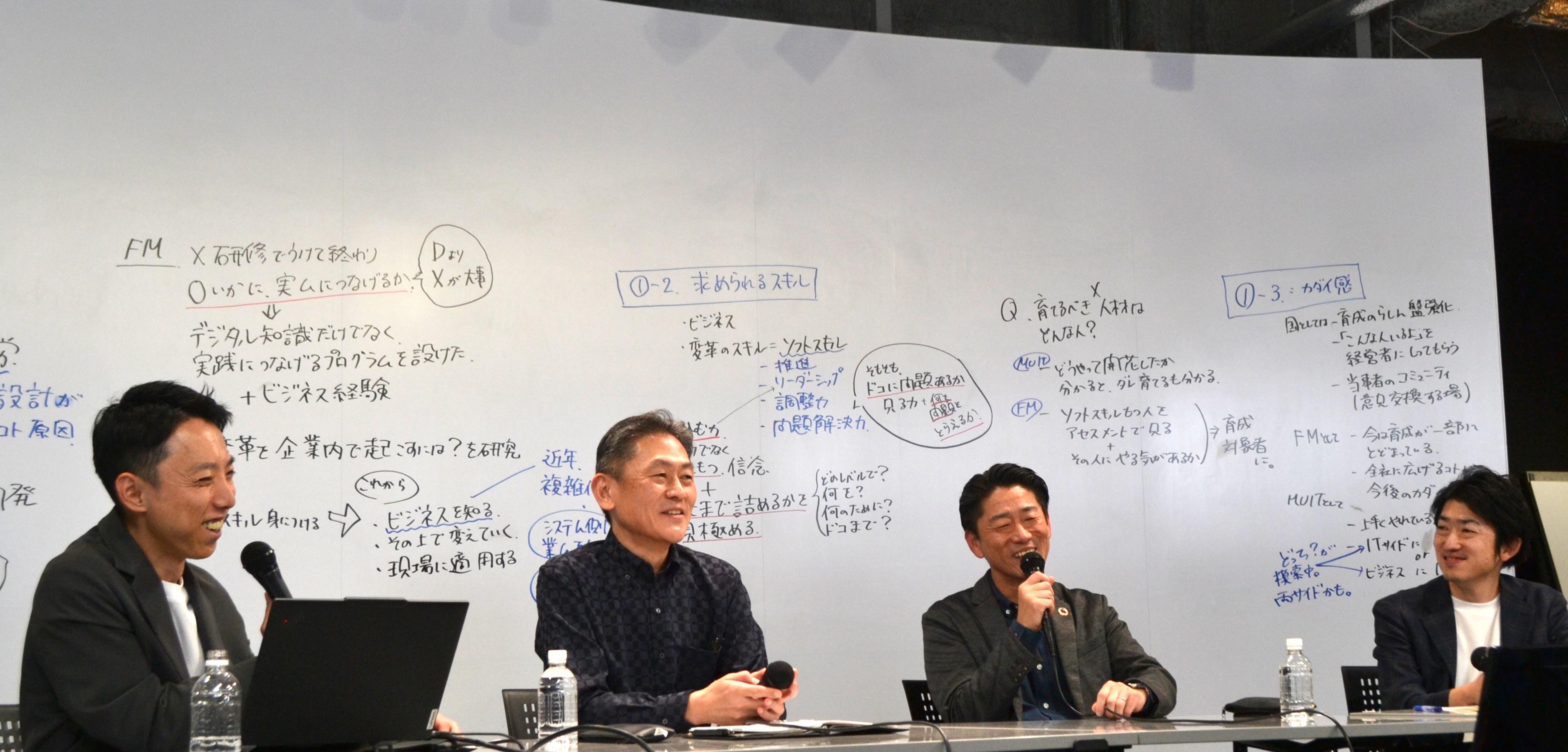 変革推進人材をテーマに、モデレーターと3名のゲストがマイクを手に、意見を交わしながら活発に議論を進める対談セミナーの様子